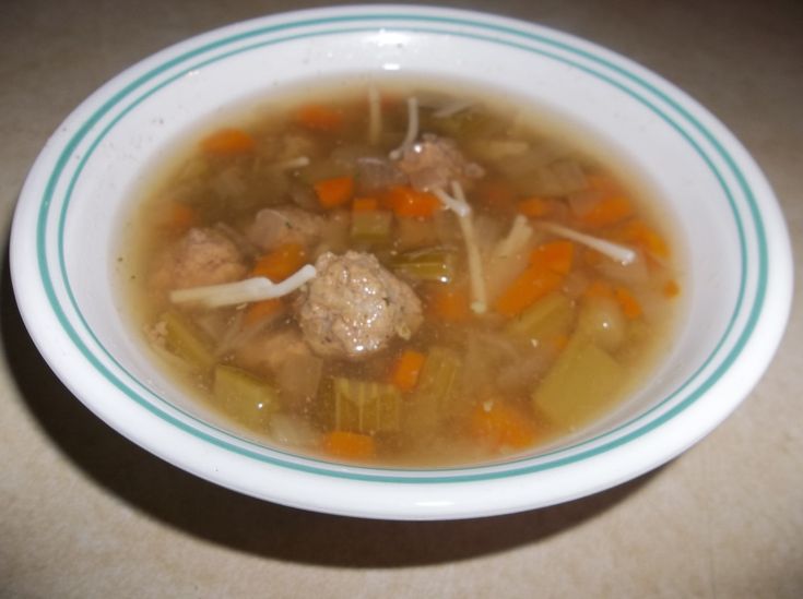 a bowl of soup with meatballs and carrots