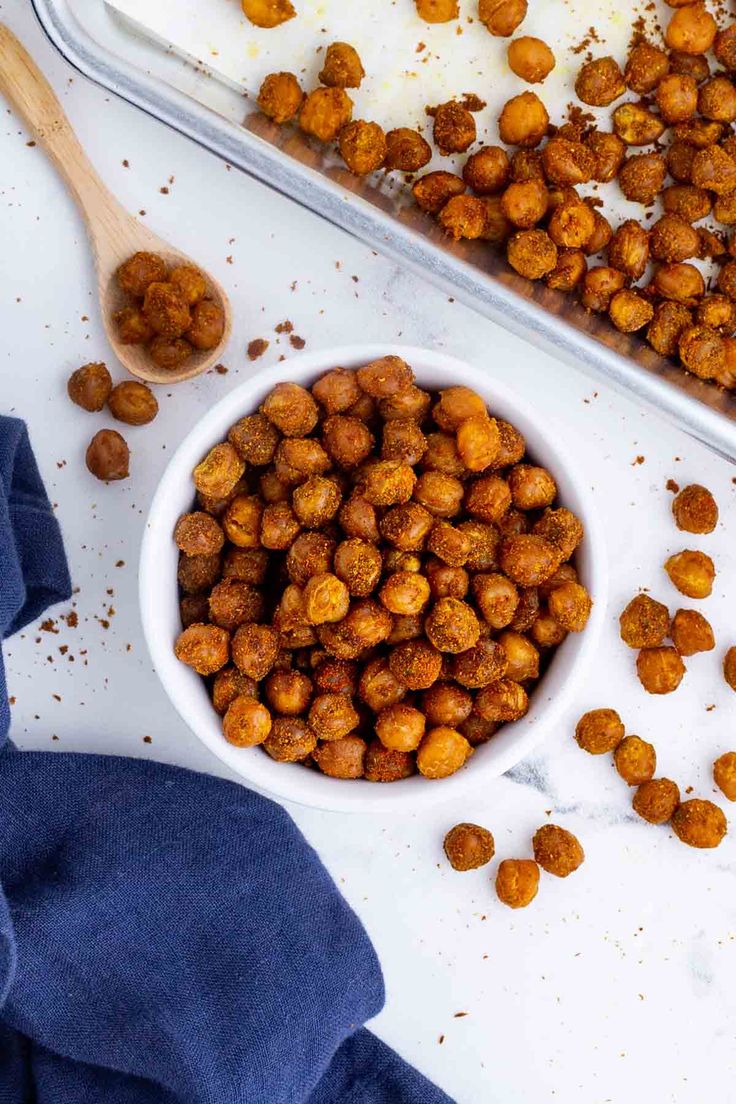 a white bowl filled with chickpeas next to a blue napkin