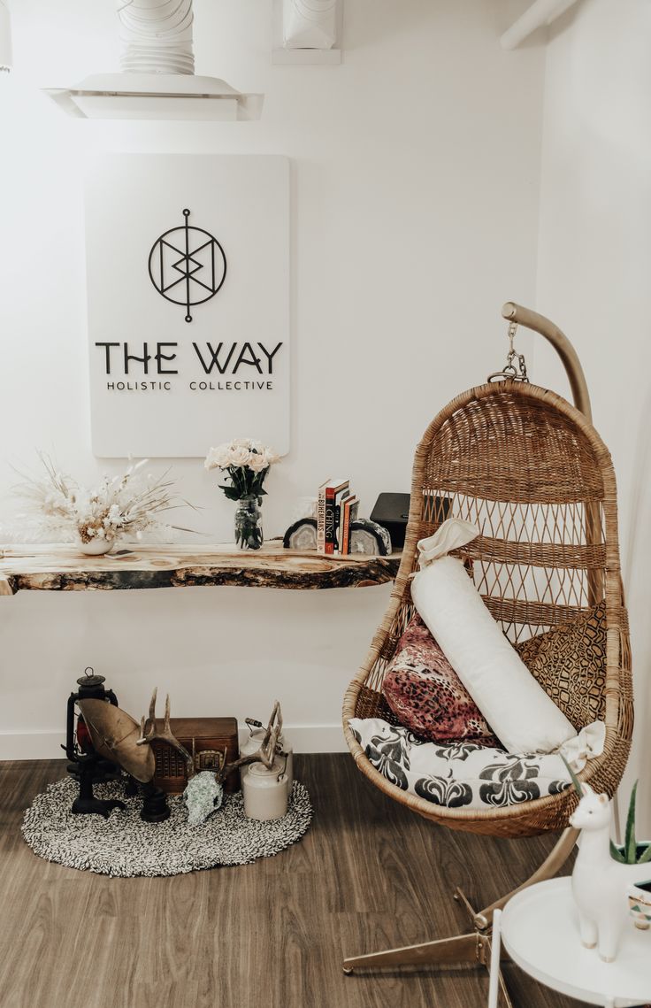 a wicker hanging chair in the corner of a room next to a wooden table