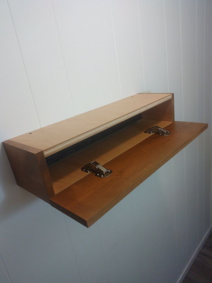 a wooden shelf with two metal handles on the wall next to a white painted wall