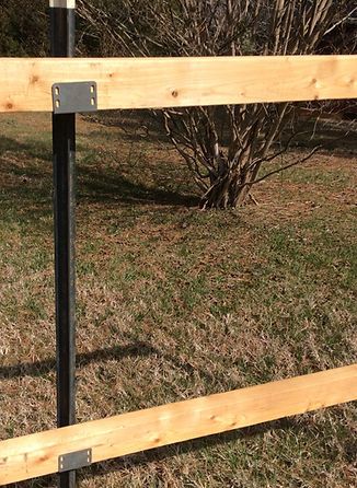 a wooden fence with metal posts in the grass