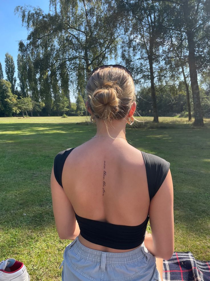 a woman sitting in the grass with her back to the camera