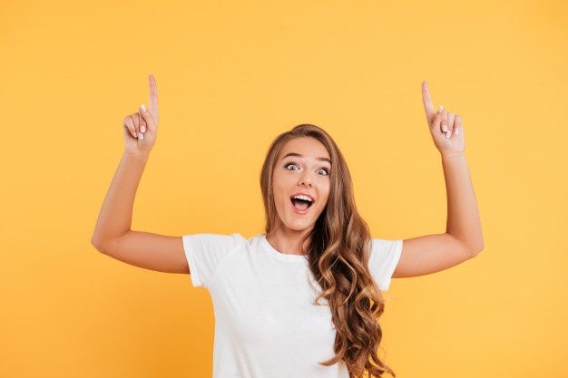 a woman with her hands up in the air while standing against an orange background,