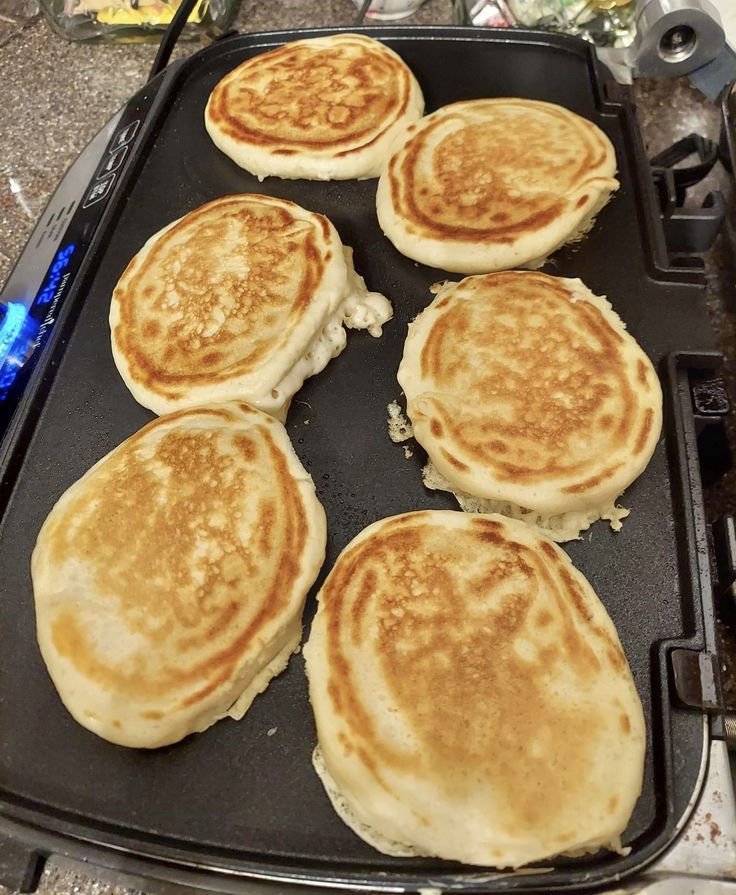 four pancakes are being cooked on a griddle