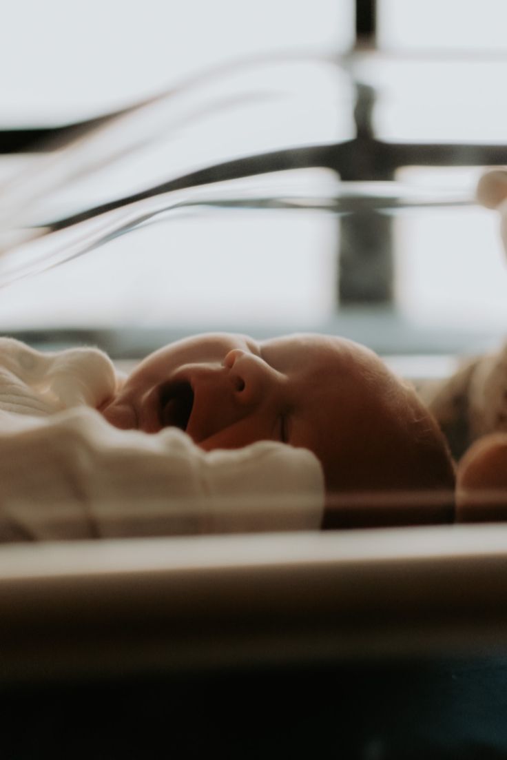 a baby is laying in a crib next to a teddy bear