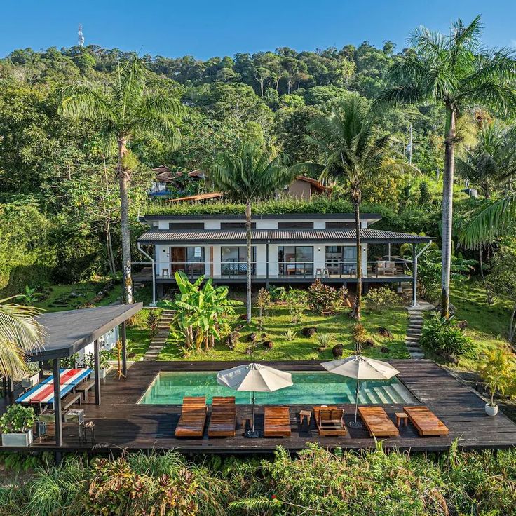 an aerial view of a house with a pool in the foreground and trees surrounding it