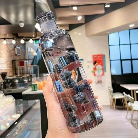 a person holding up a water bottle filled with different types of items in a store