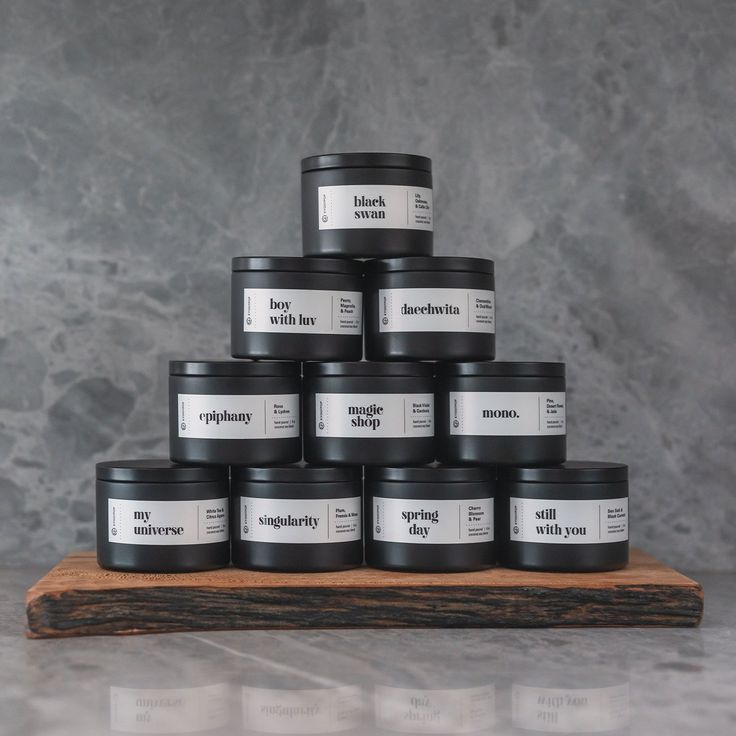 a stack of black candles sitting on top of a wooden board