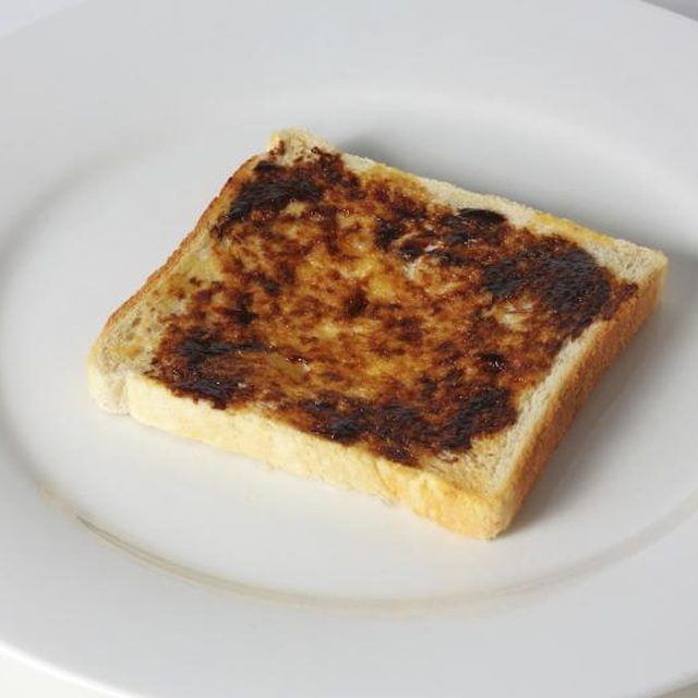 a piece of toast sitting on top of a white plate with brown stuff in it