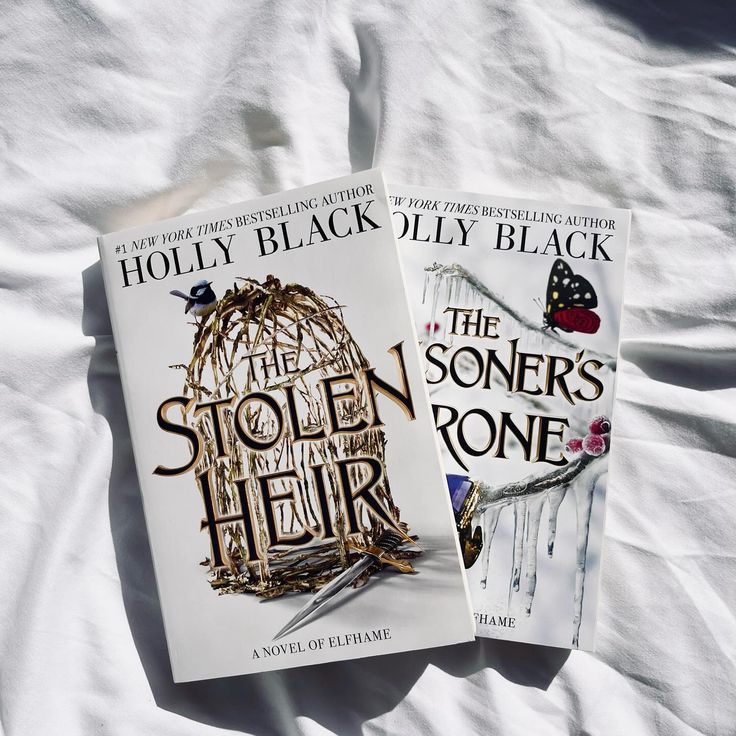 two books sitting on top of a bed next to each other, one is black and the other is white