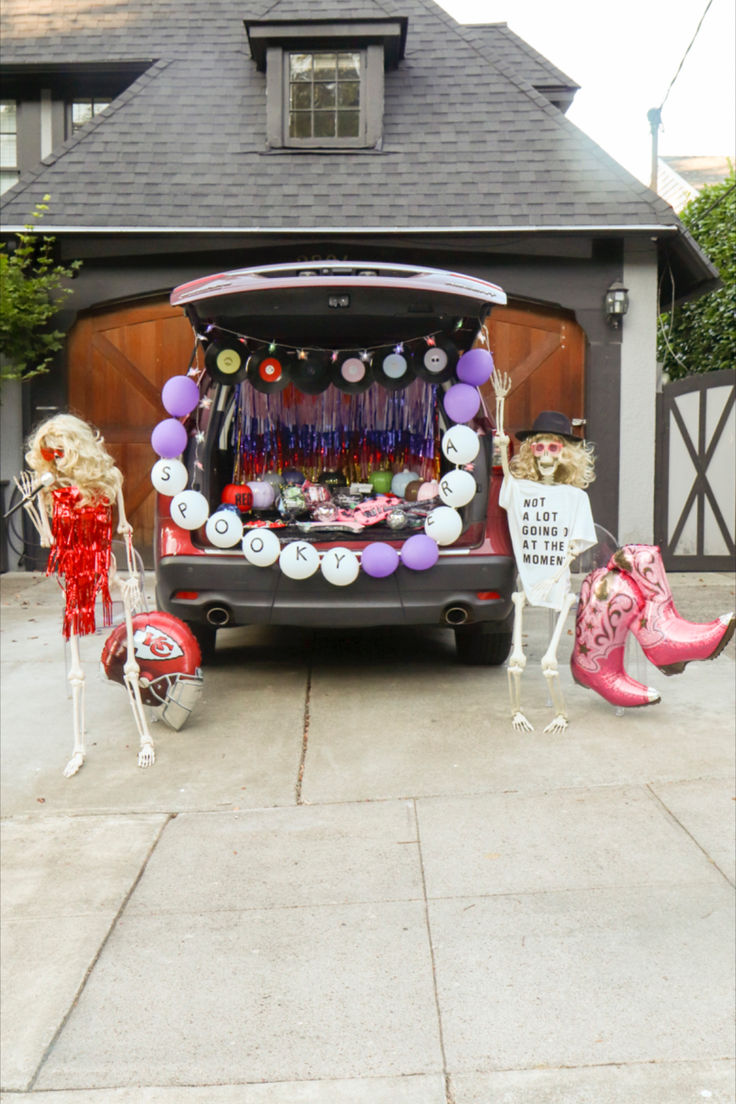 a van with decorations on the back parked in front of a house that is decorated for halloween