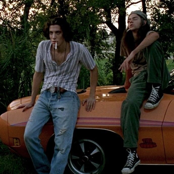 two young men sitting on top of an orange car