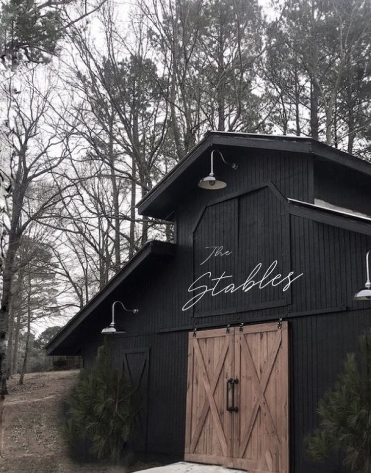 an old barn with the word stables written on it's side and two doors open