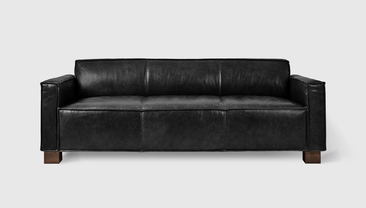 a black leather couch sitting on top of a white floor