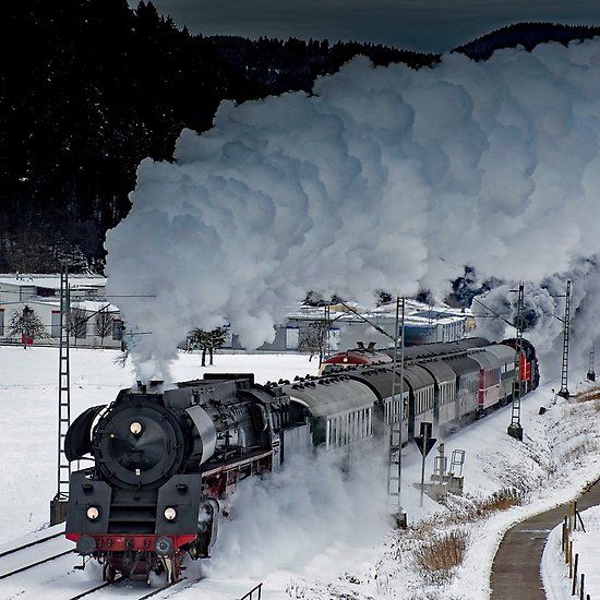 a train traveling down tracks next to snow covered ground