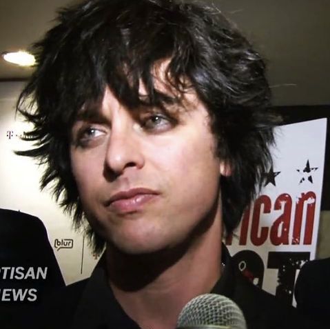 a close up of a person holding a microphone in front of a sign with an american news logo on it