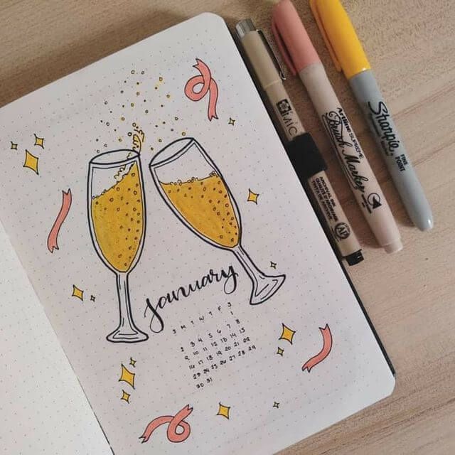 two glasses of champagne sitting on top of a notepad next to markers and pens