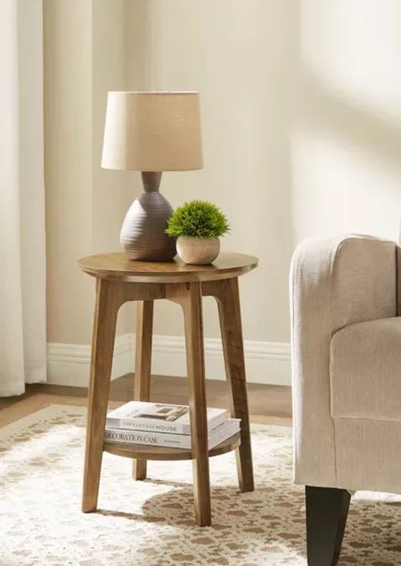 a small wooden table with a lamp on it in front of a chair and window