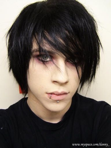 a close up of a person with black hair and piercings on his nose, wearing a black shirt