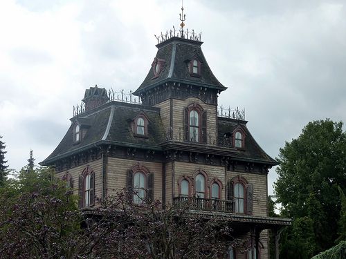 an old victorian style house with lots of windows and a clock on the top of it