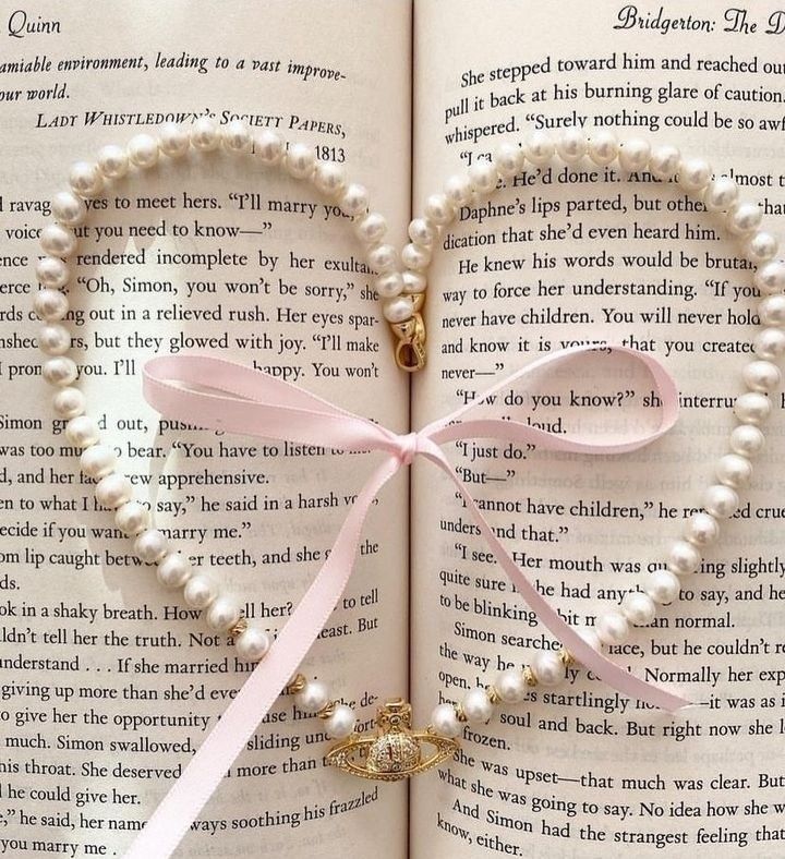 an open book with pearls and a pink ribbon