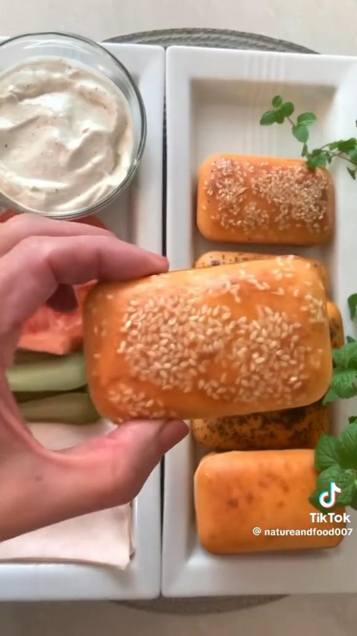 a person is holding an open sandwich in front of some vegetables and dip on the side