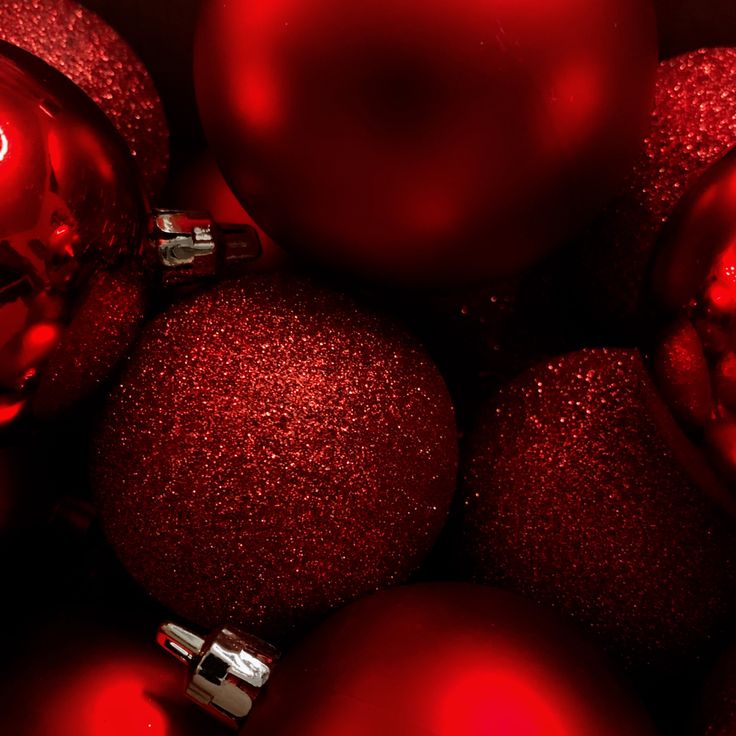 many shiny red christmas ornaments in a pile