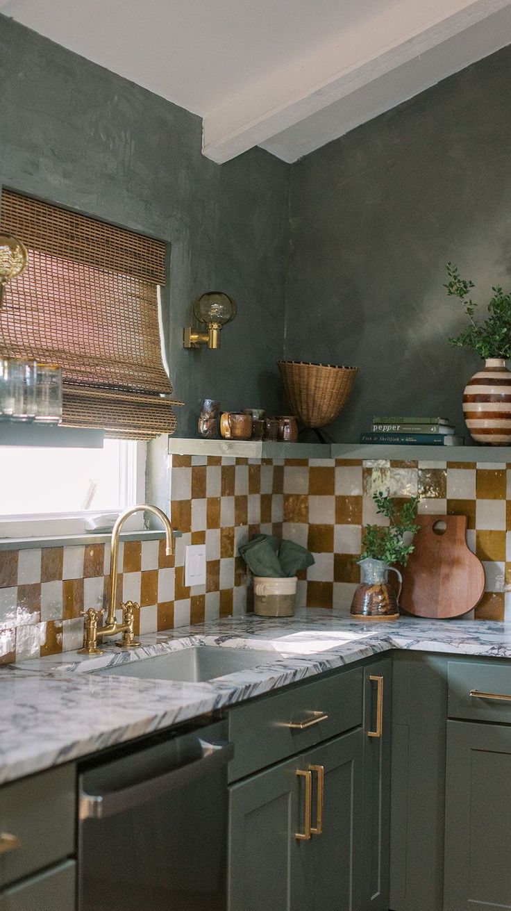 a kitchen with green cabinets and checkered tile backsplash, gold faucet