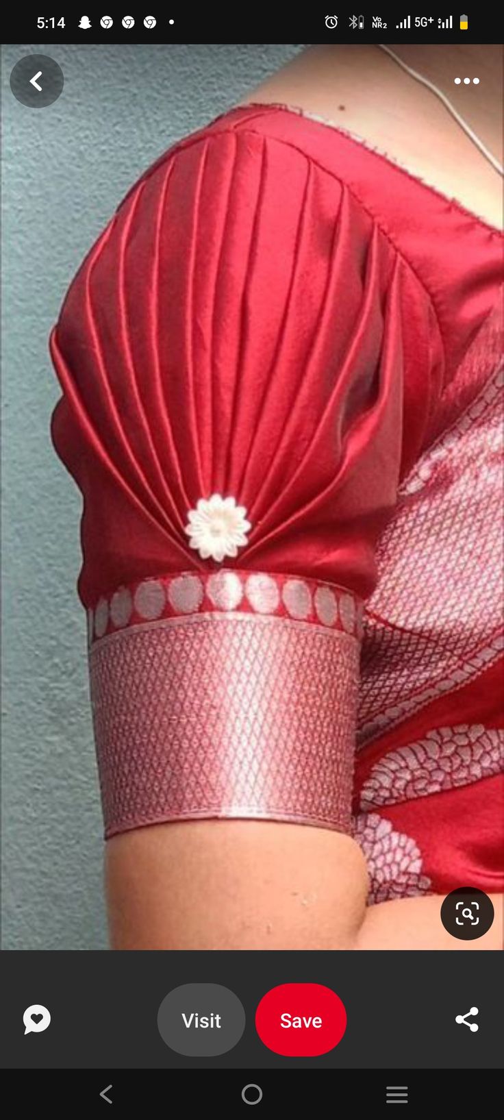 a woman wearing a red dress with a white flower in the center and her hand on her hip