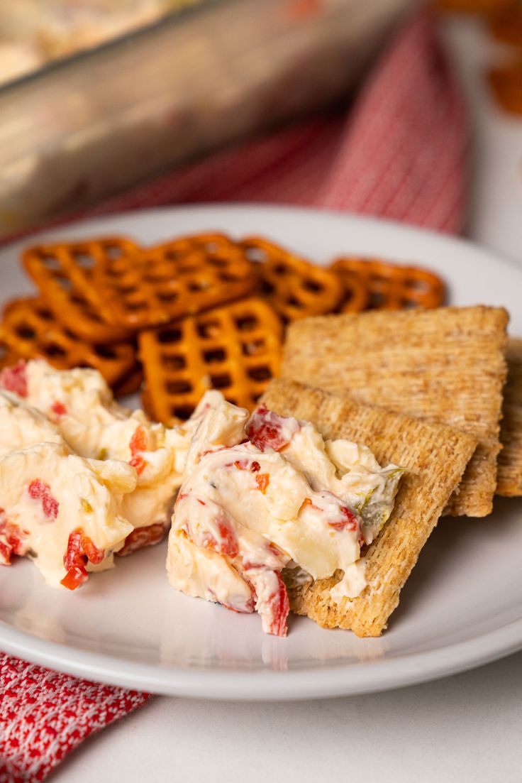 a white plate topped with crackers and crab salad next to waffles on a table