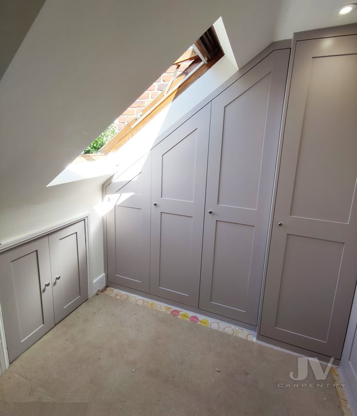 an attic bedroom with built - in closets and skylight