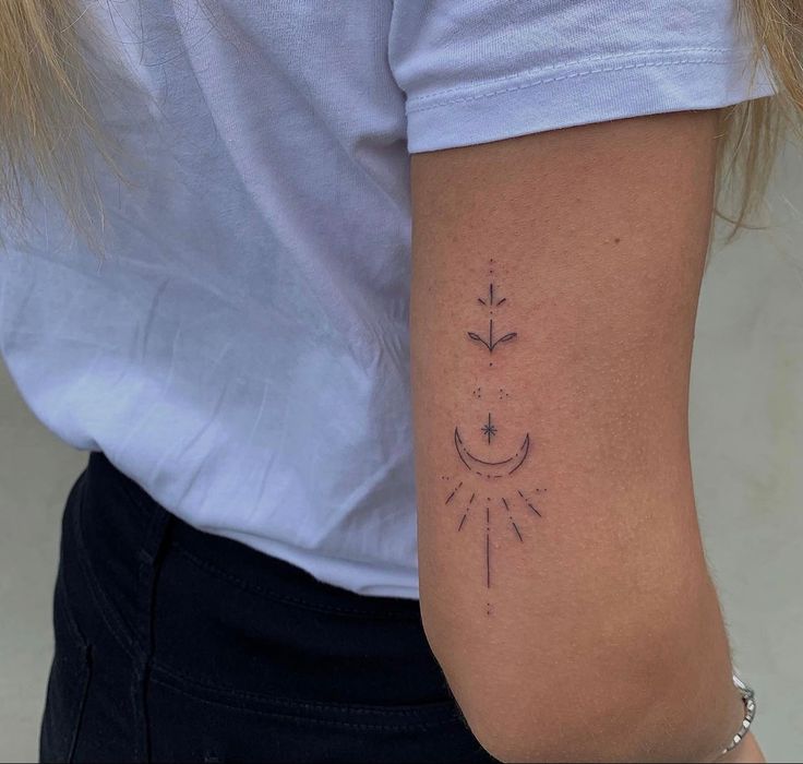 a woman with a tattoo on her arm that has an arrow and sun in it