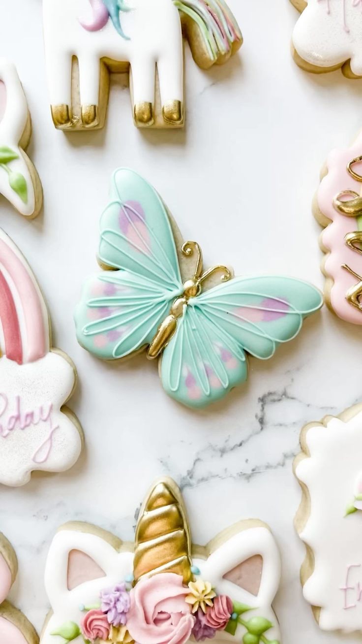 decorated cookies with unicorns, horses and flowers on a marble countertop in pastel colors