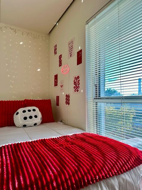 a red and white bed in a bedroom next to a window with blinds on it