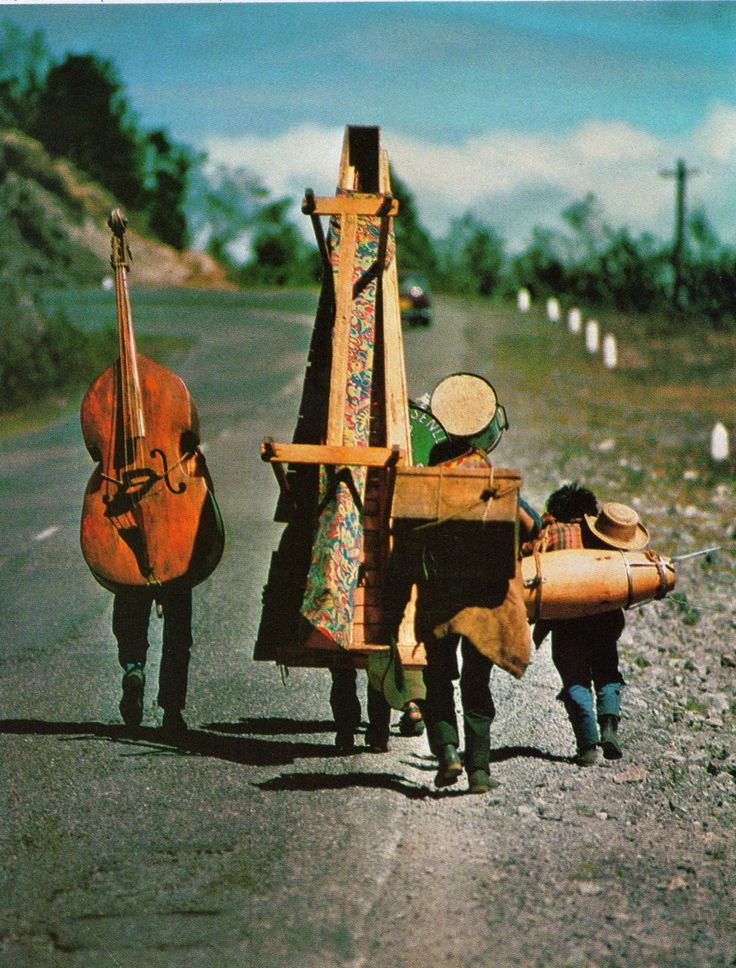 two people are walking down the road with their instruments