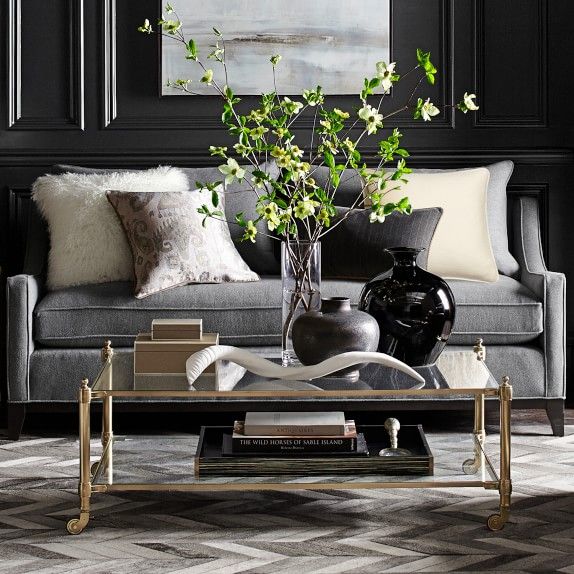 a living room with black walls and white pillows on the couches, coffee table