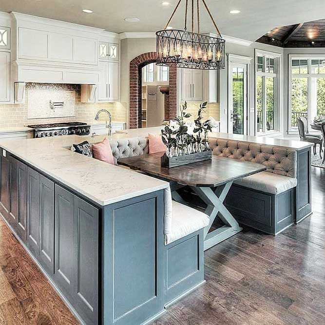 a large open concept kitchen and dining room with hardwood floors, white cabinets, an island countertop and chandelier