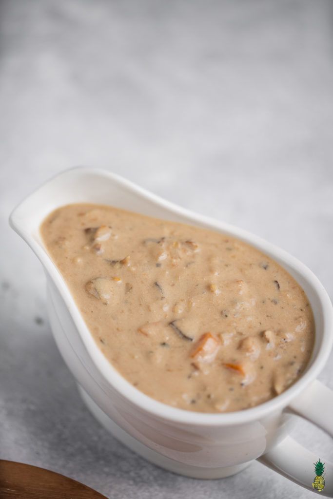 a white gravy dish with carrots in it and a wooden spoon next to it