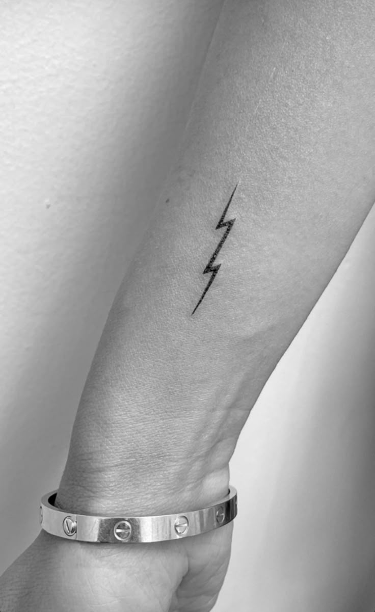 a woman's arm with a lightning bolt tattoo on the left side of her wrist