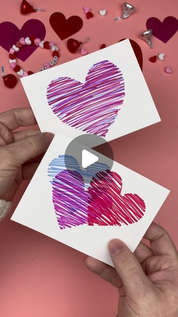 someone is holding up two cards with hearts drawn on them, and the card has been cut