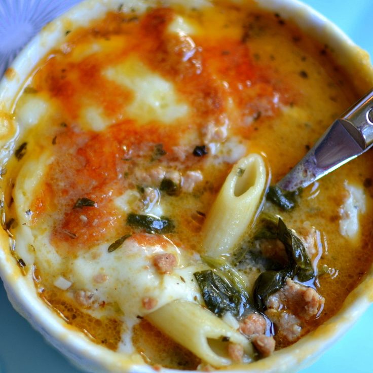 a close up of a bowl of food with pasta and spinach in it on a blue plate