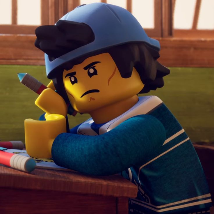 a lego character sitting at a table with a pencil