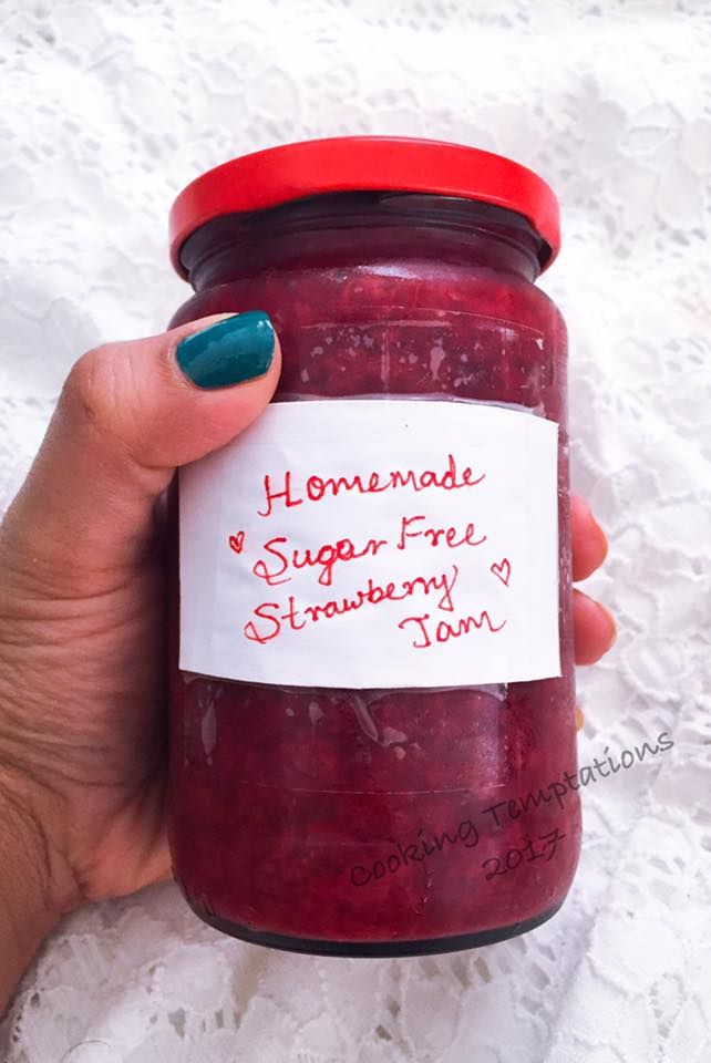 a hand holding a jar of homemade sugar free strawberry jam with a note attached to it