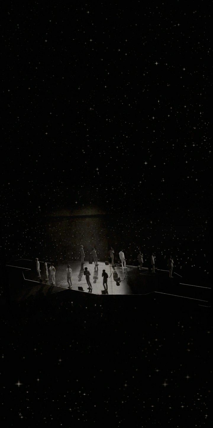 a group of people standing on top of a snow covered slope at night in the dark