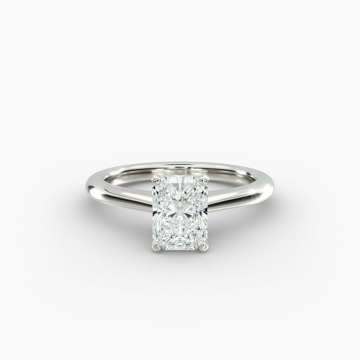 a cushion cut diamond engagement ring on a white background, with the center stone set in 18k white gold