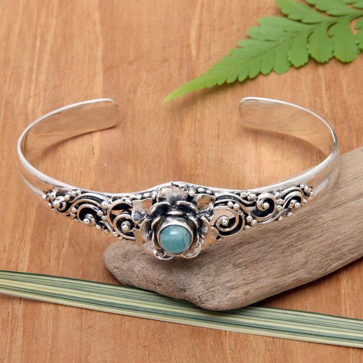 Elevate your ensemble with this stunning cuff bracelet inspired by the natural grace of flowers and adorned with a mesmerizing larimar stone. The vibrant gemstone crowns a sterling silver setting boasting intricate details and a harmonious blend of oxidized and polished finishes. Balinese artisan Buana's chic design promises to add a touch of sophistication and charm to your look. Sterling Silver Cuff Bracelet With Intricate Design For Gift, Silver Metal Cuff Bracelet With Intricate Design, Larimar Bracelet Cuff, Bohemian Silver Larimar Jewelry, Artisan Silver Multi-stone Cuff Bracelet, Bracelet Inspired, Bracelet Flower, Larimar Stone, Floral Bracelet