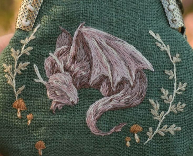 a close up of a person holding a purse with an embroidered dragon on the front