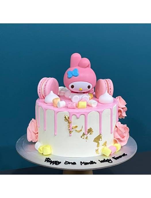 a hello kitty birthday cake with pink icing and gold decorations on the bottom tier