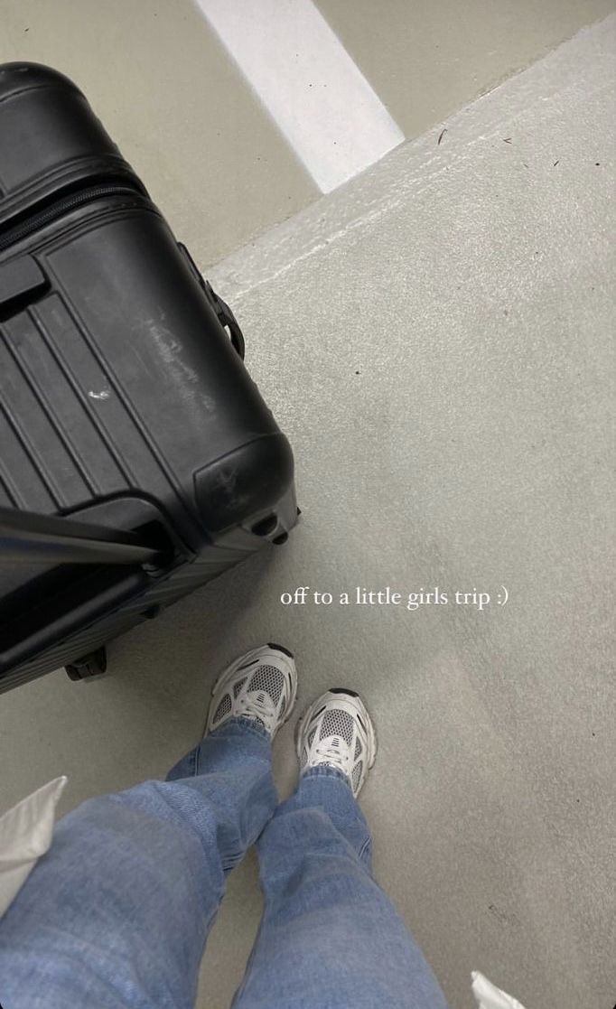 a man standing next to a black piece of luggage on top of a cement floor