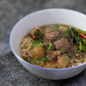 a white bowl filled with meat and noodles